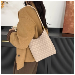 Close-up of cream woven leather hobo bag texture with golden metal buckle and shoulder strap