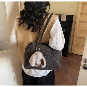 Detail of dark brown matte leather tote bag with a white plush bunny charm