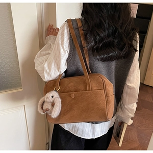 Brown suede tote bag with plush bunny charm worn by model in a minimalist style