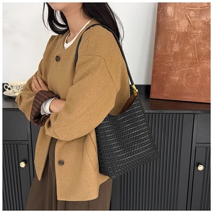 Détail d'un sac cabas en cuir tressé noir avec ferrures dorées et finitions soignées