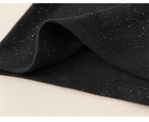 Detailed macro view of black sequined fabric showing the wide hem and neat stitching