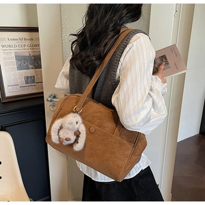 Detailed macro view of retro brown PU leather tote bag with white plush bunny charm