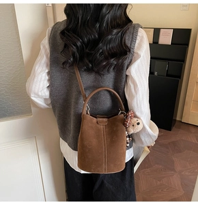 Detail of vintage brown suede bucket bag with round handle and teddy bear charm