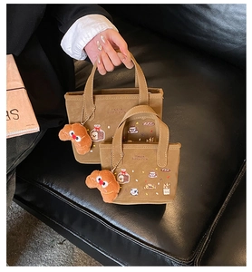 Détail du sac à main en toile marron avec broderie boulangerie et porte-clés croissant