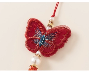 Vue détaillée de la broderie papillon rouge avec fils d'or et perles blanches