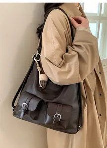 Detail view of dark brown tote bag with two front pockets and a pinecone charm