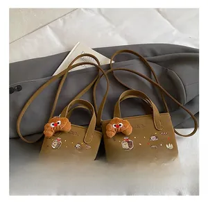 Détail d'un sac marron avec broderie de pain et charmant pendentif croissant doux
