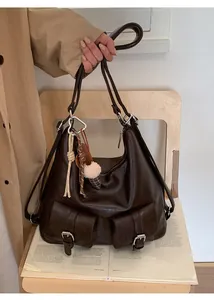 Detail of dark brown retro leather hobo bag with front buckle pockets and charm