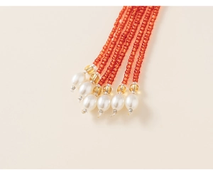 Détail du gland perlé sur robe de style chinois avec perles oranges et blanches