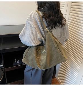 Detail view of large olive green suede tote bag featuring floral embroidery and gathered top