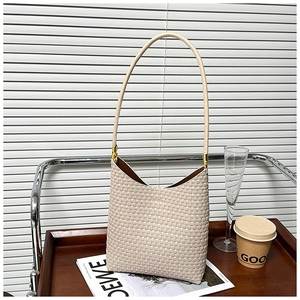 Detail view of cream woven shoulder bag texture with golden hardware in a lifestyle setting
