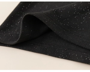 Detail of black girl shirt fabric featuring silver glitter sequins and fine stitching