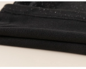 Close-up of black sleeveless vest with sparkly glitter fabric and warm fleece lining