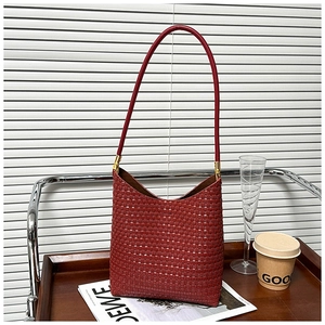 Detail shot of a dark reddish brown woven leather tote with golden metal hardware
