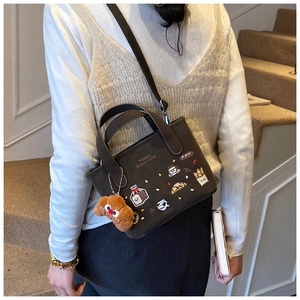 Détail du sac cabas en toile marron avec broderie de pain et breloque chien peluche
