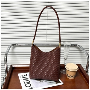 Detailed close-up of dark brown woven leather texture and elegant shoulder strap on a hobo bag