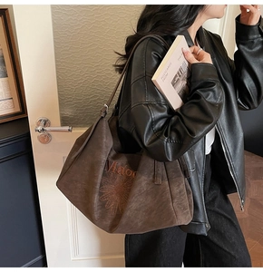 Detail of embroidered daisy on large brown suede tote bag with stylish wide shoulder strap
