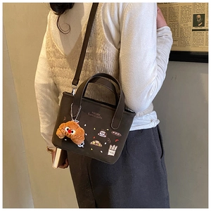 Détail d'un sac bandoulière marron foncé avec broderie et charmant pendentif en peluche croissant