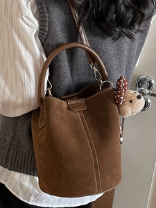 Retro dark brown suede bucket bag with plush bear charm and adjustable shoulder strap