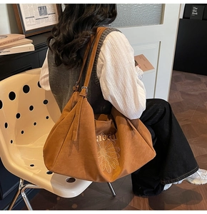 Close-up of large brown suede tote bag with daisy embroidery and adjustable straps