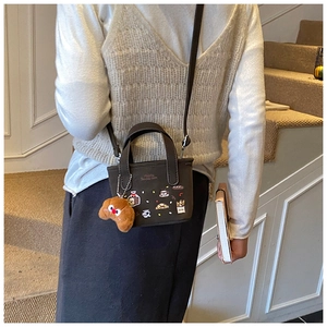 Détail du sac bandoulière marron café avec écussons dessin animé et charm croissant peluche