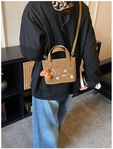Détail d'un petit sac vintage marron avec broderie cartoon et breloque croissant en peluche