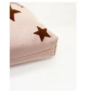 Close-up detail of reinforced bottom corner with brown star flocking on beige tote bag