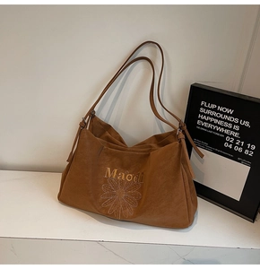 Close-up of brown suede tote bag with white daisy embroidery and Maodi brand logo