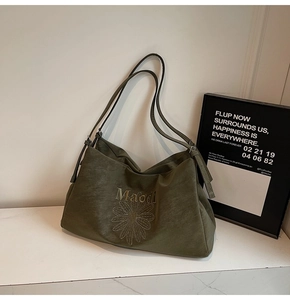 Close-up of olive green tote bag featuring daisy print and adjustable silver buckles