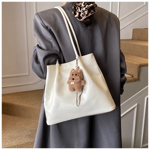 Nahaufnahme der weißen Leder-Tote-Bag-Struktur mit einem süßen Bären-Anhänger