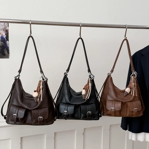 Close-up of vintage tote bags with matte leather texture and decorative front flap pockets