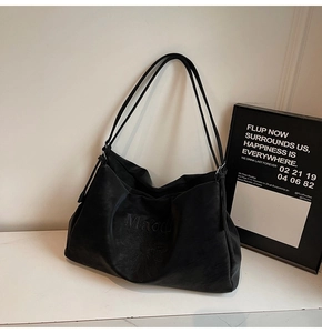 Detail of black tote bag with Marodi lettering and floral embroidery on soft material