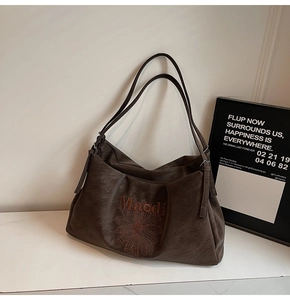 Close-up of dark brown tote bag featuring orange floral embroidery and Maodi branding