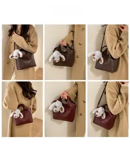 Detail view of retro bucket bags in dark brown and wine red with plush bunny charms