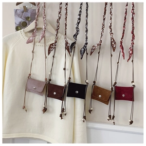 Detail of mini suede crossbody bags with silk scarf straps and decorative wooden beads