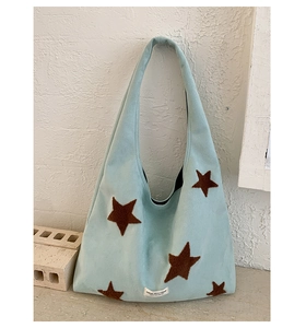 Detail view of the star embroidery and texture of the light blue plush tote bag
