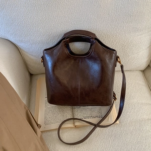 Detailed view of dark brown vintage leather bucket bag texture and fine vertical stitching