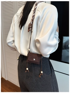 Detail of mini dark brown suede crossbody bag with wood beads and checkerboard scarf decoration