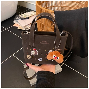 Détail du sac à main en cuir marron avec broderies cartoon et pendentif croissant en peluche