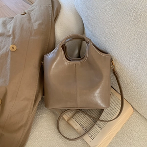Close-up of mocha leather bucket bag showing round handle and gold metal hardware
