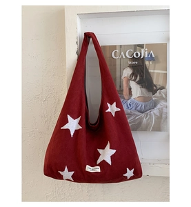 Detail of red plush tote bag with white star embroidery and CREME label
