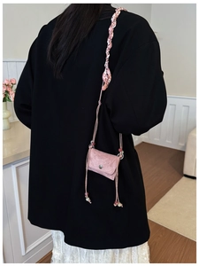 Detail view of pink micro crossbody bag with woven strap and silk ribbon on model