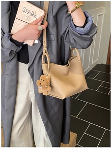 Vue détaillée du sac seau en cuir camel avec un pendentif chien en peluche et anneaux dorés
