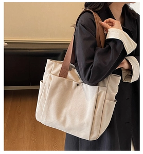 Détail du sac cabas en toile beige avec trois poches latérales et des anses marron durables