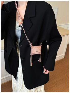 Pink suede mini crossbody bag with decorative scarf and beaded strap on a model