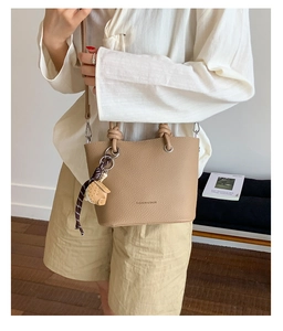 Close-up of khaki pebbled leather bucket bag with top handle and cute animal charm
