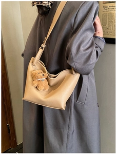 Détail d'un sac seau en cuir de couleur chameau avec un charmant ours en peluche brun