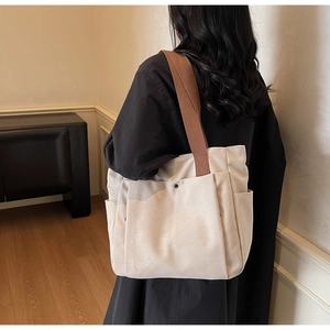 Detail of canvas tote bag with side pocket and brown strap worn by a female model