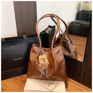 Detail der dunkelbraunen Leder-Shopper-Tasche mit einem süßen Plüschhund-Anhänger