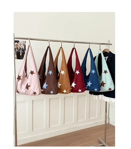 Row of colorful star embroidered canvas tote bags hanging on a stainless steel rack